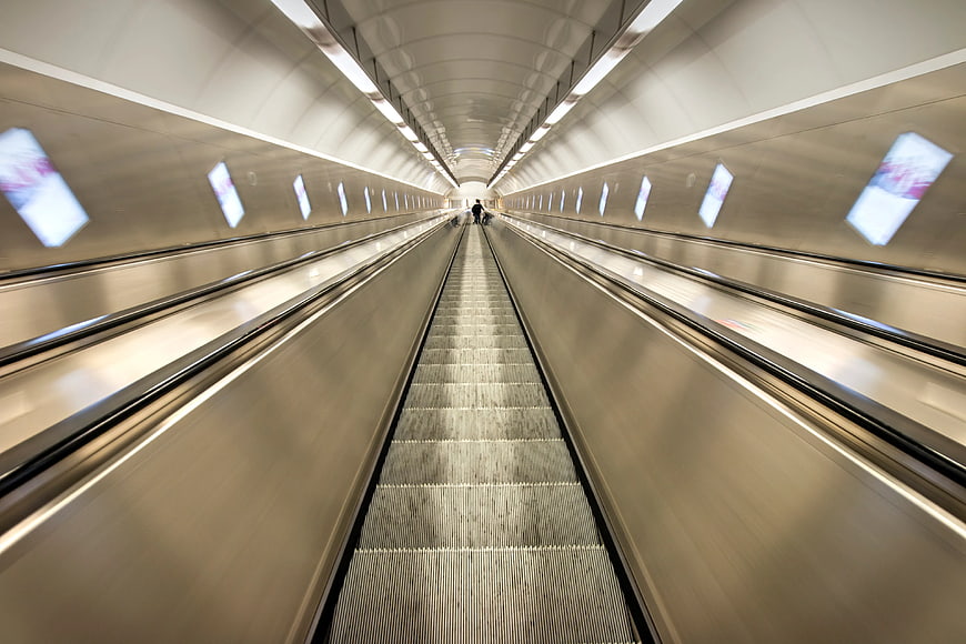 Motion blur escalator tunnel with leading lines and distant figure