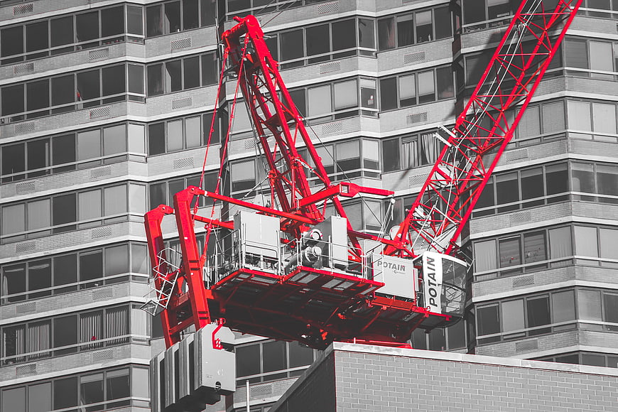 Red Construction Crane Against Black and White Building