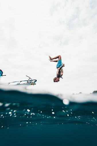 Man doing backflip off boat into ocean water