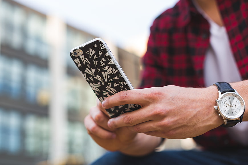 Man using smartphone with patterned case and wristwatch