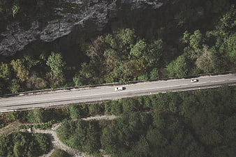 Aerial View of Cars Driving on Mountain Road Through Forest