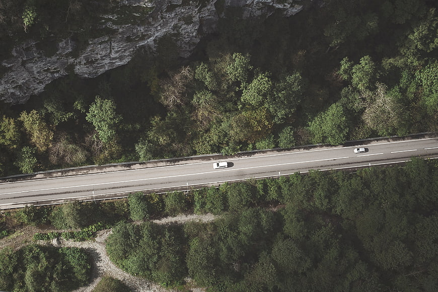 Aerial View of Cars Driving on Mountain Road Through Forest
