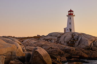 White Lighthouse on Rocky Coast at Sunset