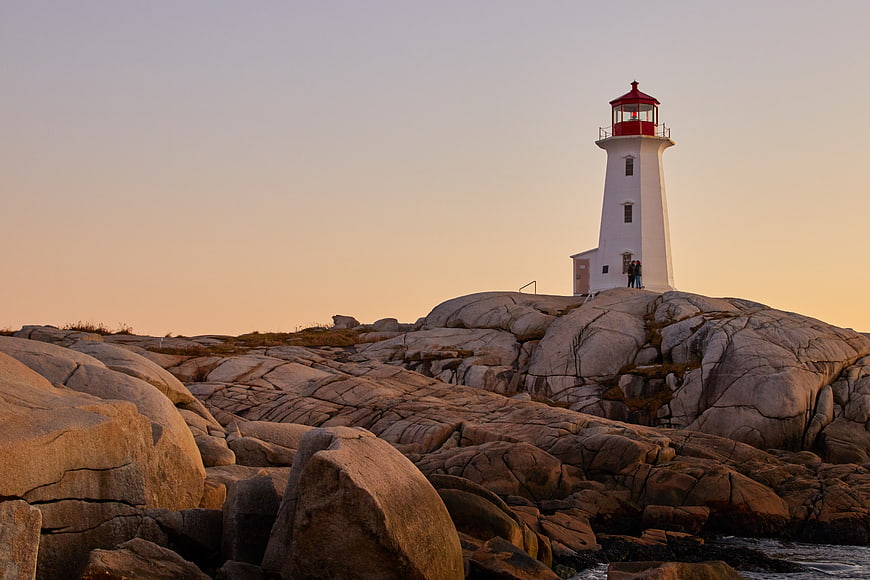White Lighthouse on Rocky Coast at Sunset