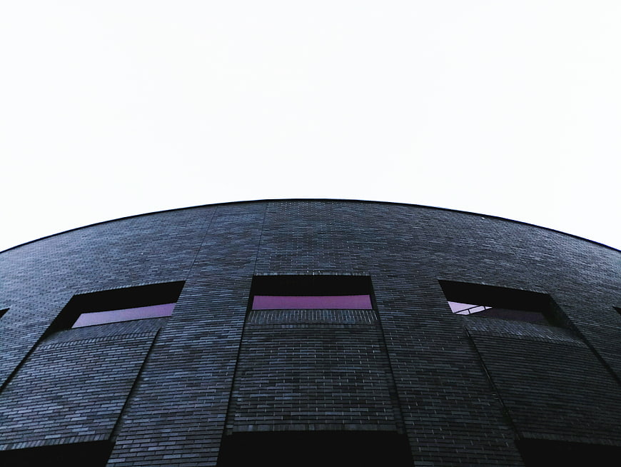 Low angle view of modern curved dark brick building facade