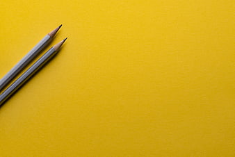 Two Grey Pencils on Yellow Background with Copyspace