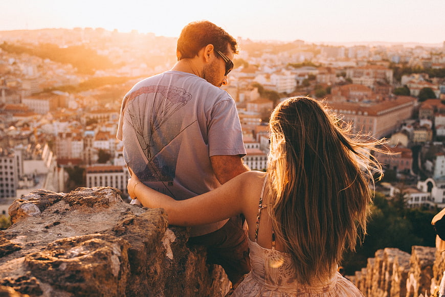 Couple watching sunset over city skyline from viewpoint