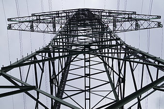 Low angle view of steel electricity pylon against gray sky