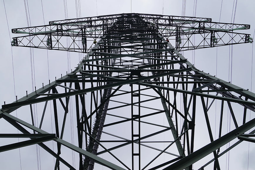 Low angle view of steel electricity pylon against gray sky