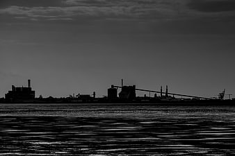 Silhouette of industrial harbor skyline over dark water