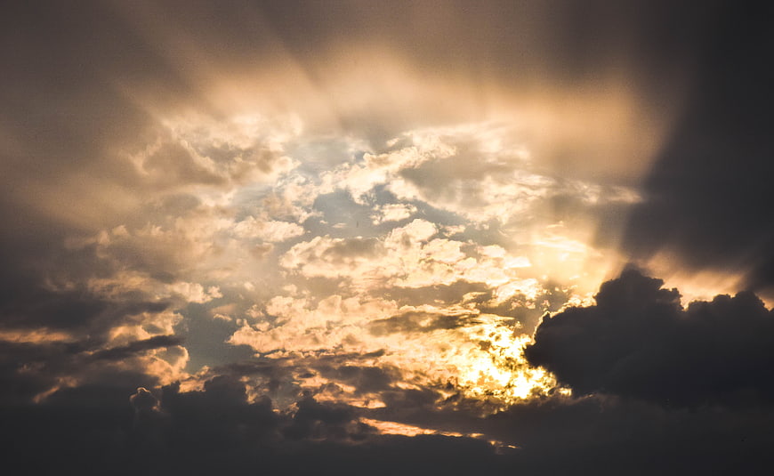 Dramatic Sunbeams Breaking Through Dark Clouds at Sunset