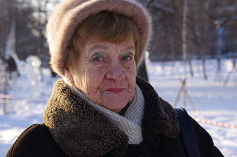 Portrait of elderly woman in winter fur hat and scarf outdoors