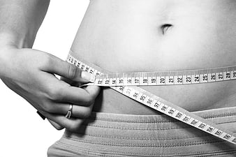Woman measuring waist with tape measure for fitness