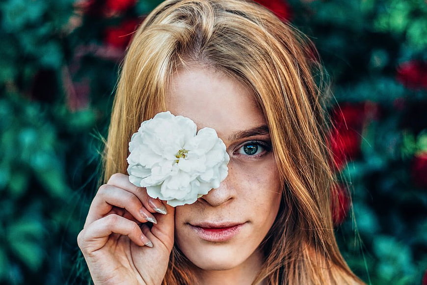 Woman Holding White Flower Over Eye in Garden