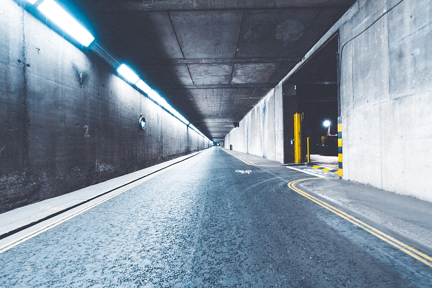 Empty concrete tunnel with blue neon lights and asphalt road