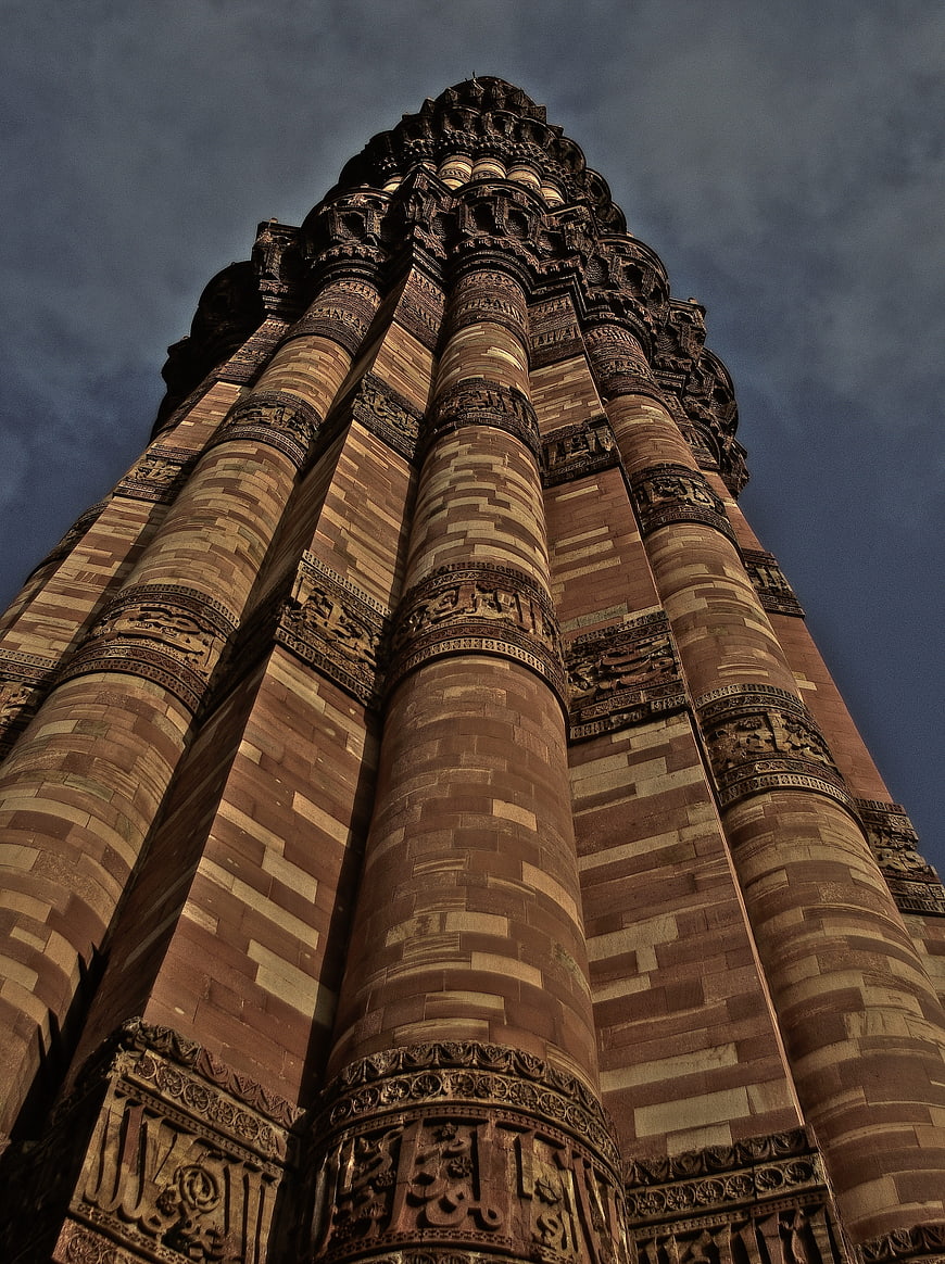 Low angle view of Qutb Minar stone tower against dark sky