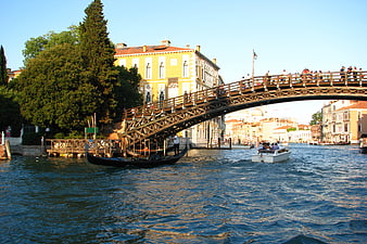 Gondola passing under wooden bridge in Venice canal