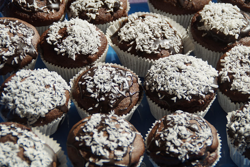 Close-up of chocolate muffins topped with shredded coconut and chocolate drizzle