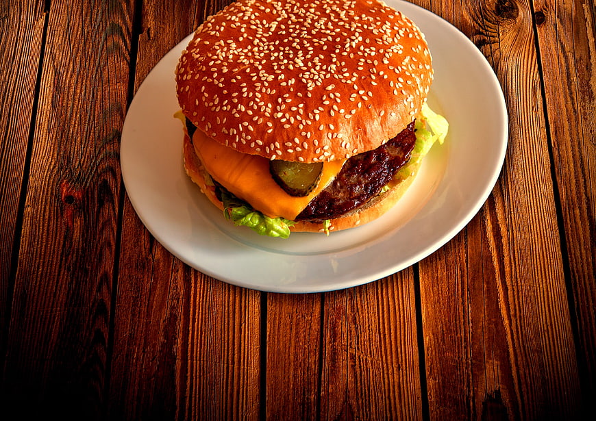 Delicious Cheeseburger on White Plate with Wooden Background
