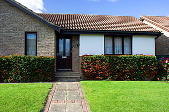 Modern brick bungalow with green lawn and red tiled roof