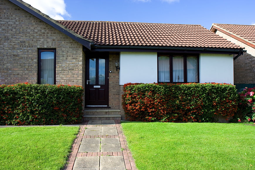 Modern brick bungalow with green lawn and red tiled roof