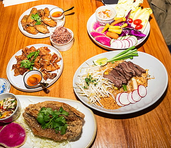 Overhead view of Thai feast with pad thai, wings, and fried fish