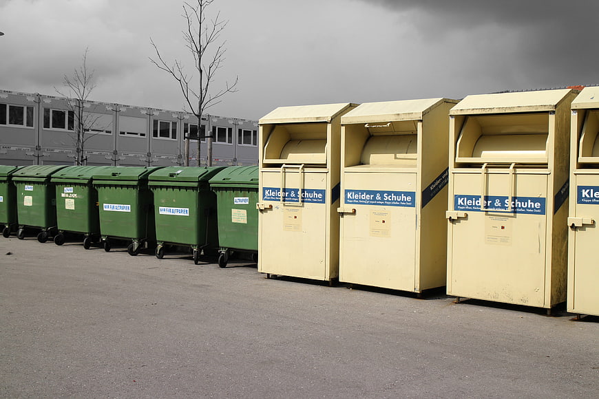 Row of green and beige waste disposal containers in an industrial yard