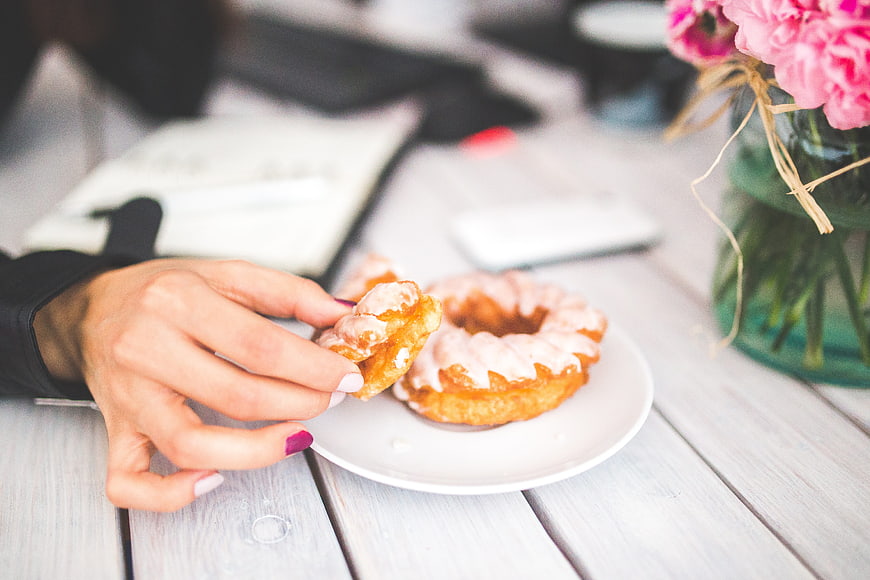 Woman's Hand Holding Glazed Donut on White Plate