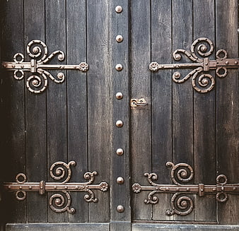 Antique wooden door with ornate wrought iron hinges