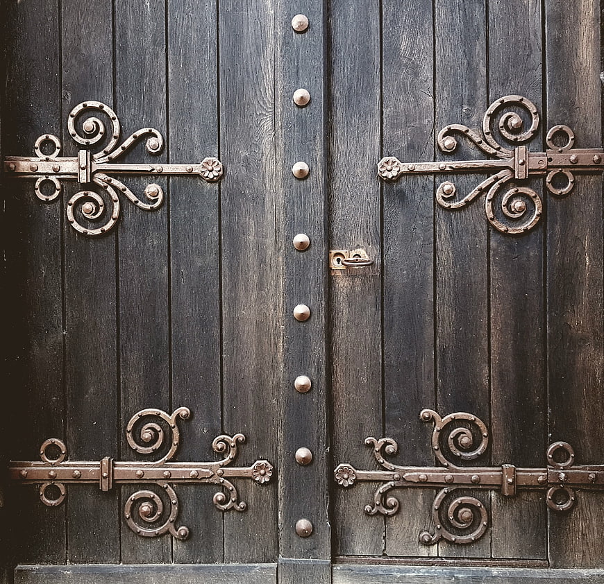 Antique wooden door with ornate wrought iron hinges