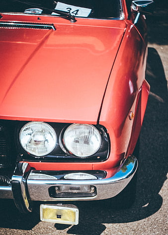 Close-up of vintage red classic car front bumper and headlights