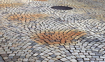 Textured Cobblestone Pavement with Circular Pattern and Manhole Cover
