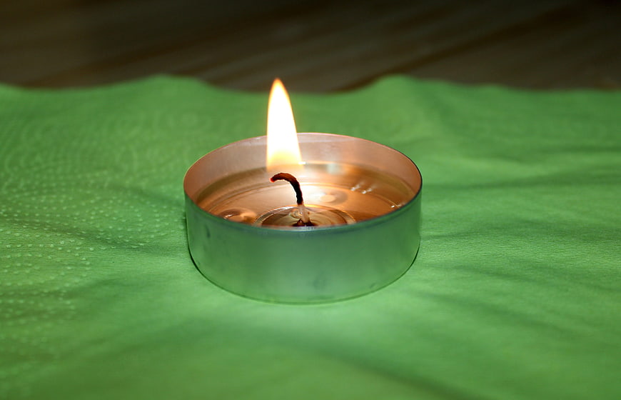 Tealight candle burning on green textured cloth