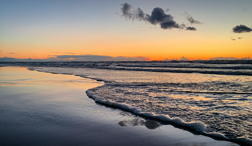 Serene Sunset Beach with Gentle Waves and Reflections
