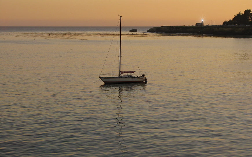 Sailboat Anchored in Calm Bay at Golden Sunset