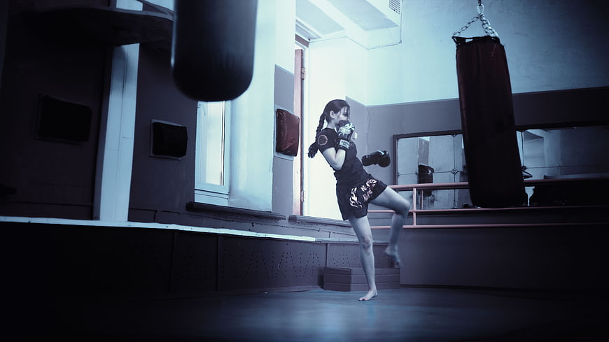 Female Kickboxer Training in Dim Gym