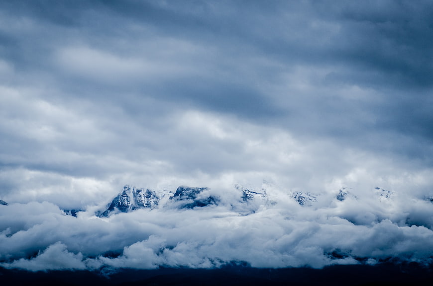 Snowy mountain peaks emerging from thick clouds