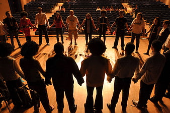 Group of people holding hands in a circle on a stage