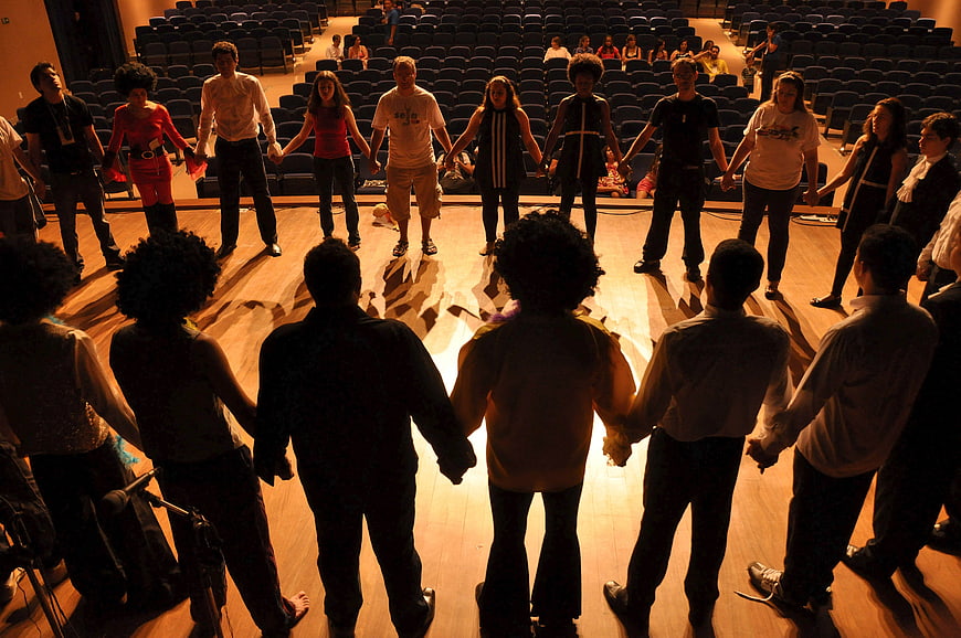Group of people holding hands in a circle on a stage