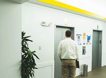 Man waiting for elevator in modern office hallway