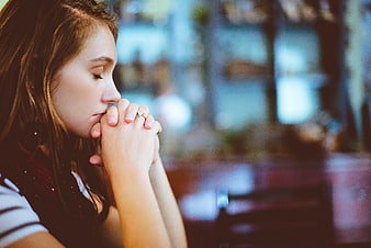 Young woman praying with hands clasped in profile