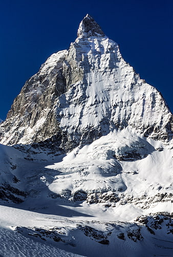Matterhorn mountain peak covered in snow against blue sky