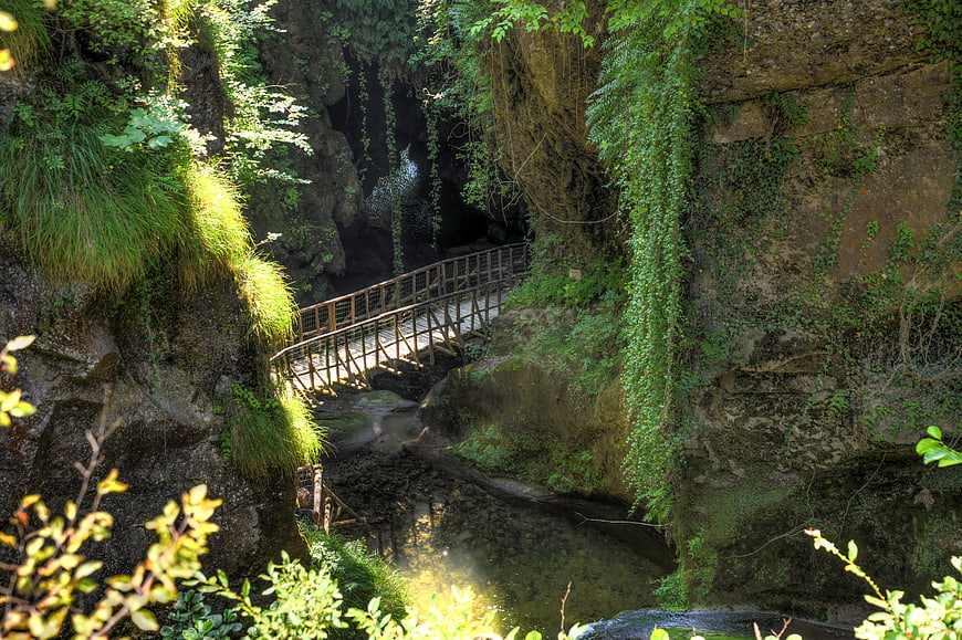 Wooden bridge crossing a lush green river gorge
