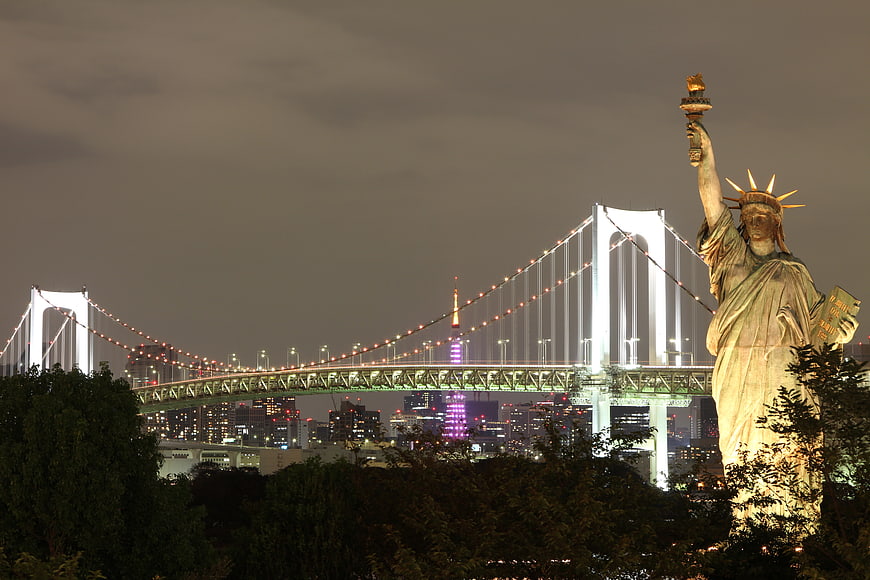 Statue of Liberty replica with Rainbow Bridge and Tokyo Tower at night