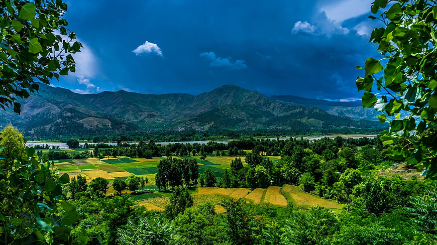 Vibrant Green Valley Landscape with Mountains and Dramatic Blue Sky