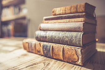 Stack of vintage leather-bound books on a rustic wooden table