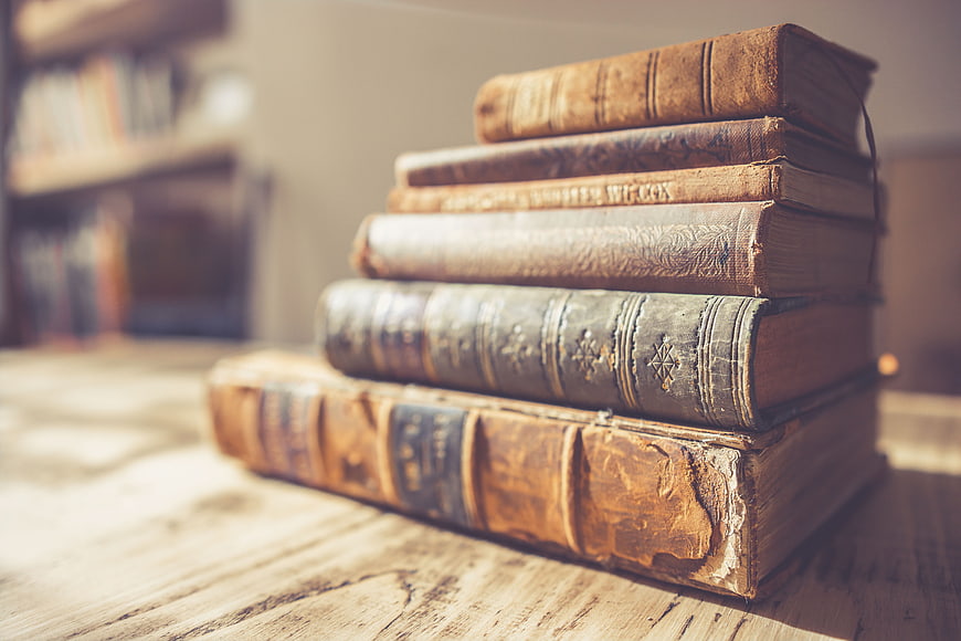 Stack of vintage leather-bound books on a rustic wooden table
