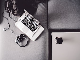 Top view of laptop and headphones on gray sofa