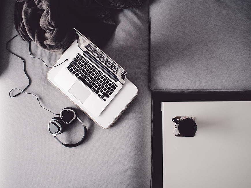 Top view of laptop and headphones on gray sofa