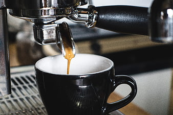Espresso pouring from portafilter into black cup